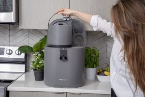 A person lowering the bucket into the FoodCycler.