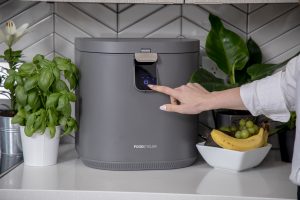 A person pressing start on the FoodCycler.
