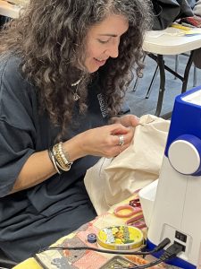 Claudia De Sousa Baptista mending a piece of clothing by hand.