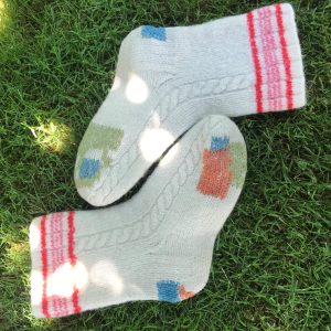 A pair of socks visibly darned and repaired by Alder & Alder.